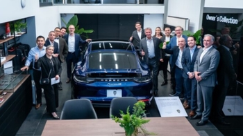 Grupo de personas posando junto a un Porsche Panamera E-Hybrid azul en una concesionaria, posiblemente durante una presentación o entrega del vehículo.