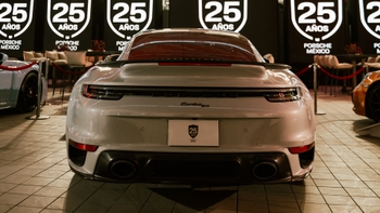 Vista trasera de un Porsche 911 Turbo S blanco en la celebración del 25 aniversario de Porsche México, mostrando su diseño y detalles.