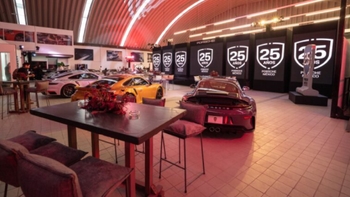 Interior de un evento de Porsche México con varios coches Porsche y decoración del 25 aniversario.