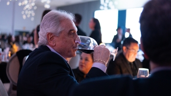 Hombre mayor bebiendo vino tinto en copa durante la cena del evento.