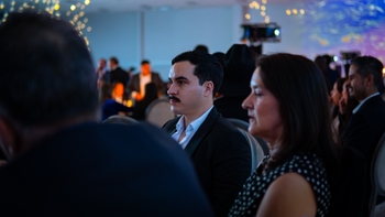 Público atento en la ceremonia, plano medio de asistentes sentados escuchando el evento.