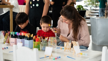 Mujer ayudando a niños a pintar en un evento de arte.