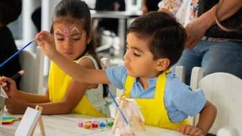 Niños pintando lienzos en un evento artístico infantil.