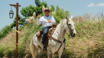 Man riding a horse smiling while getting his picture taken