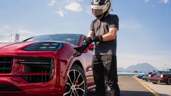 Piloto de carreras al lado de un auto Porsche de color rojo