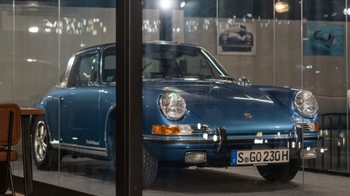 this is a blue classic Porsche on display in glass