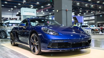 Porsche 718 Cayman azul vibrante en exposición en un salón de autos, mostrando su diseño deportivo.