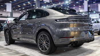 Parte trasera de un Porsche Cayenne Coupé gris en exposición, resaltando su línea de techo inclinada y luces traseras.