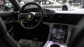 Interior de un Porsche eléctrico, mostrando el volante, el tablero digital y la pantalla central con información de batería y autonomía.