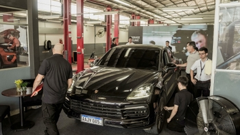 Taller de servicio Porsche con técnicos revisando un Porsche Cayenne negro durante una Service Clinic.