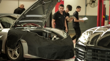 Mecánicos trabajando en el motor de un Porsche en un taller de servicio técnico.