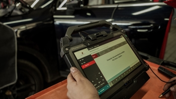 Técnico de Porsche utilizando una tablet para diagnóstico y mantenimiento de un Porsche Cayenne.