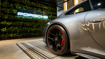 Porsche 911 gris de la parte trasera en un concesionario moderno con alfombra de diseño y detalles lujosos.