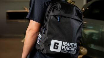 Mochila negra con diseño Martini Racing Porsche, llevada por una persona, mostrando detalles del logo y la marca.